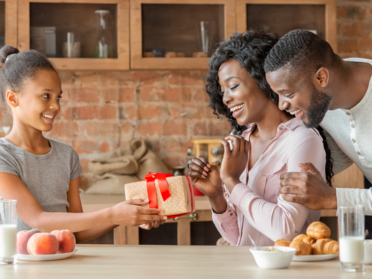 Excited woman receiving personalized gifts from her family - custom tumblers, mugs, keychains, shirts, glasses, bracelets, and more.